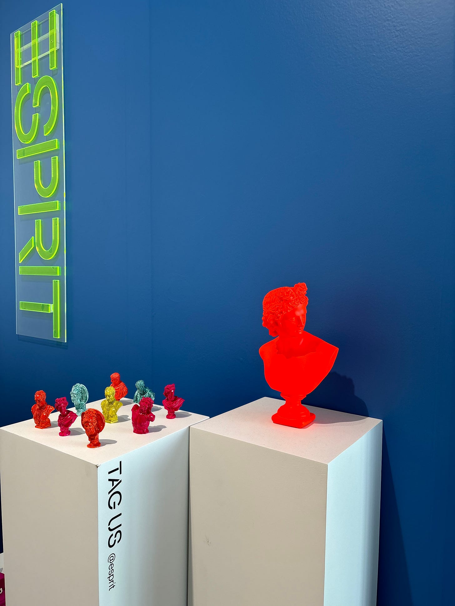 Esprit gallery installation: neon green wall sign and resin figurine sculptures on plinths