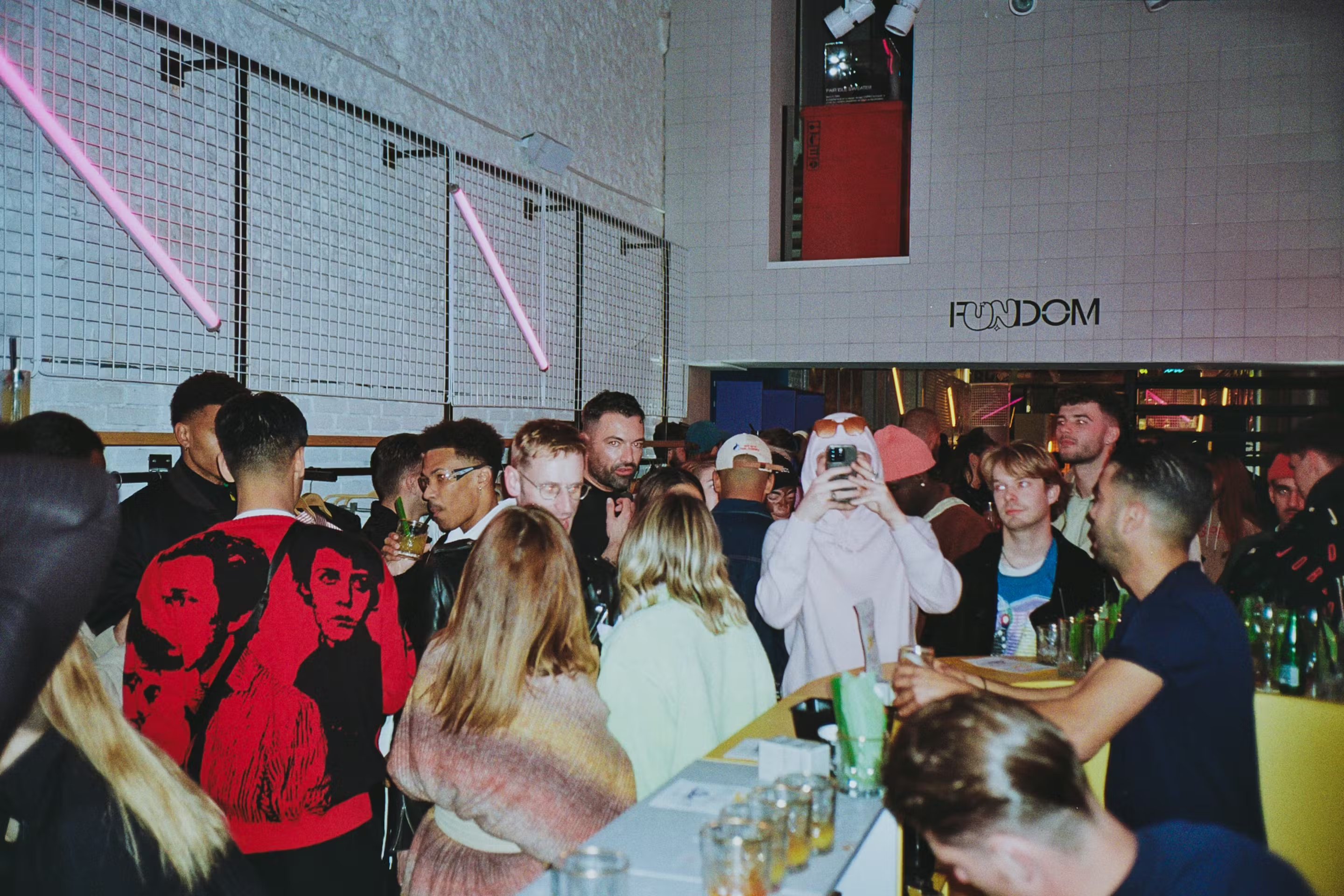 Crowd at FUNDOM, the Esprit event series, beneath neon tube lighting and FUNDOM signage